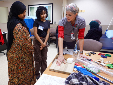  Therapist shows two students different tools in lab